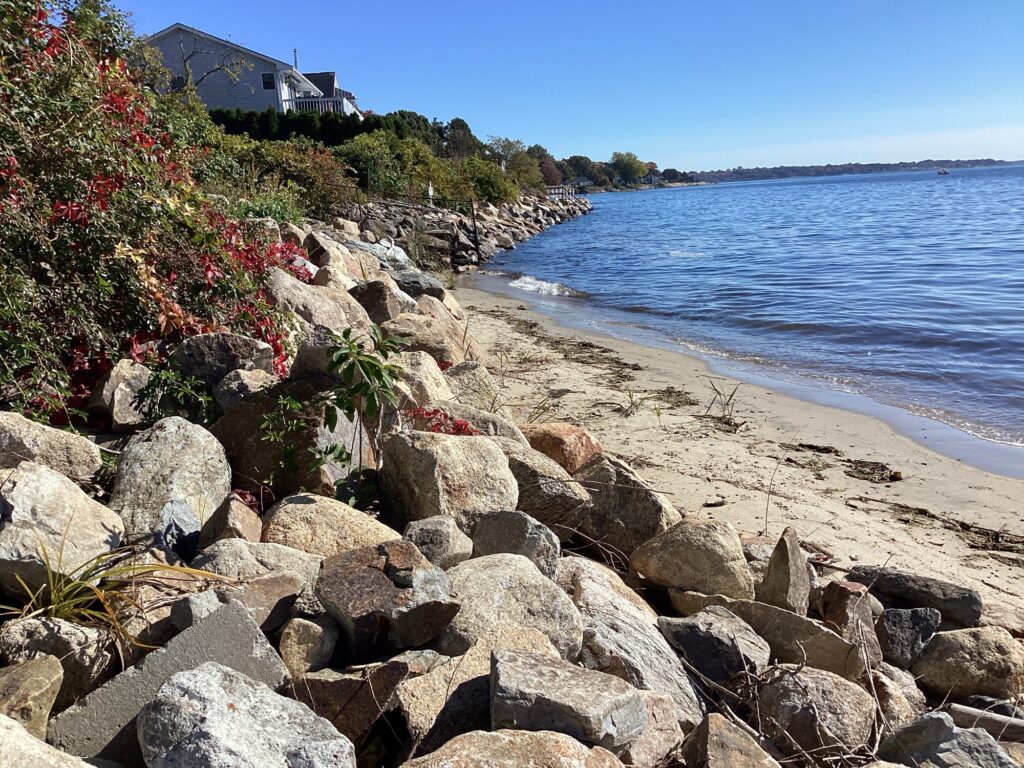 a rocky beach with a house in the background (MyCoast AI)