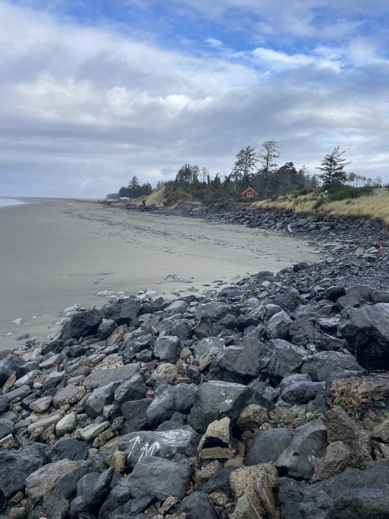 a rocky beach with a house in the distance (MyCoast AI)