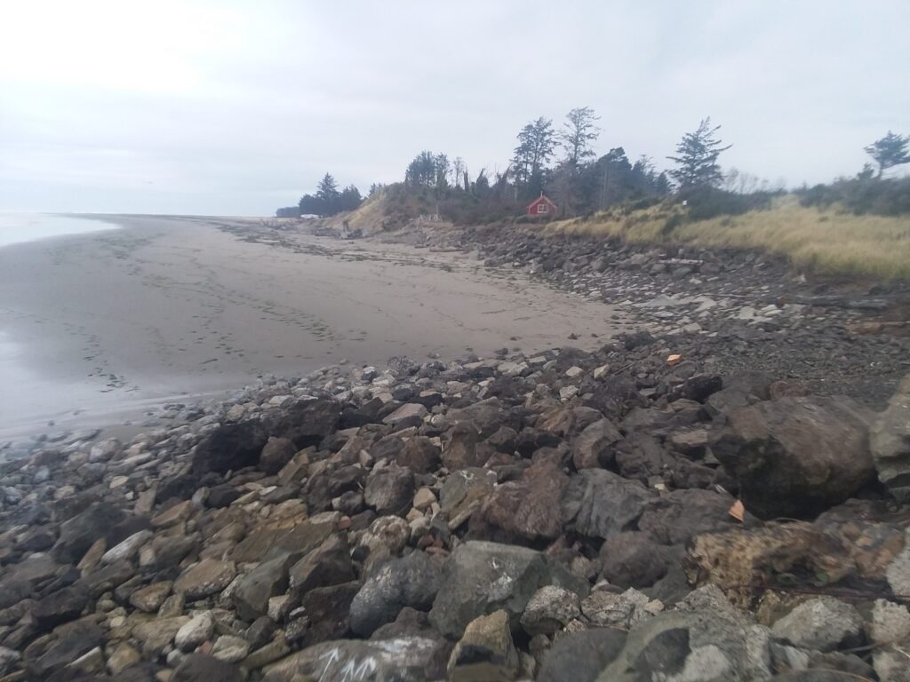 a rocky beach with a house in the distance (MyCoast AI)