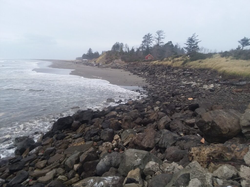 a rocky beach with a house in the distance (MyCoast AI)