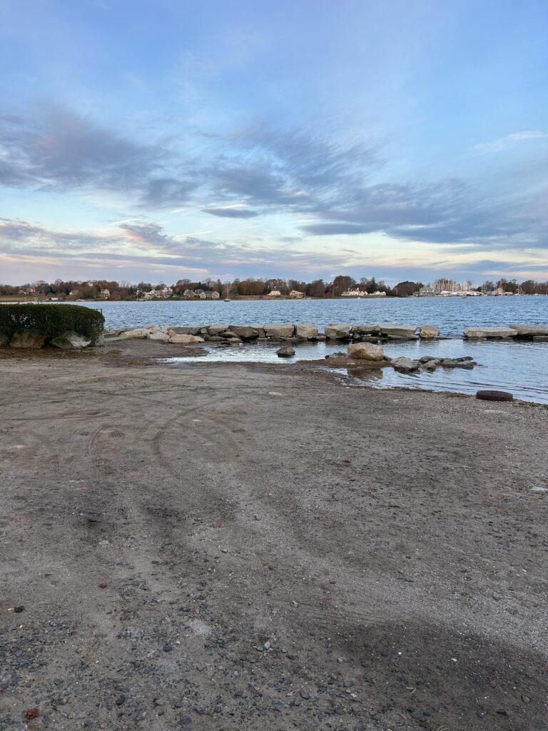 a rocky beach with a body of water and trees in the background (MyCoast AI)