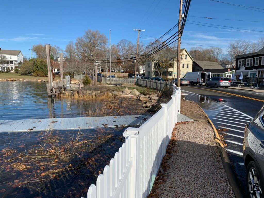 a road with a white railing and a body of water with houses on the side (MyCoast AI)