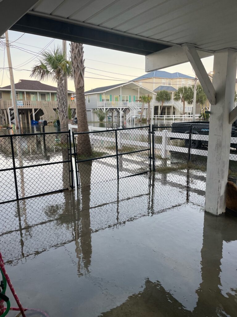 a wet street with a fence and buildings in the background (MyCoast AI)