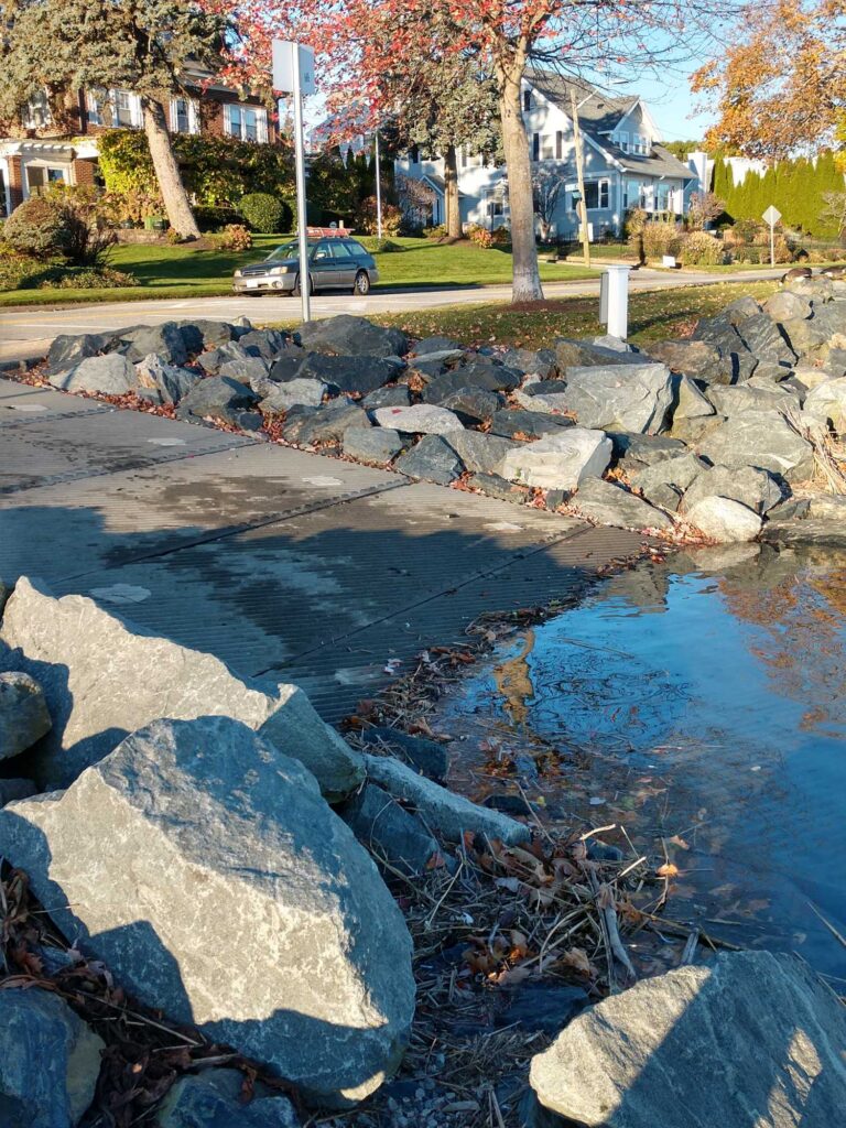 a small pond with rocks and a car parked in the background (MyCoast AI)
