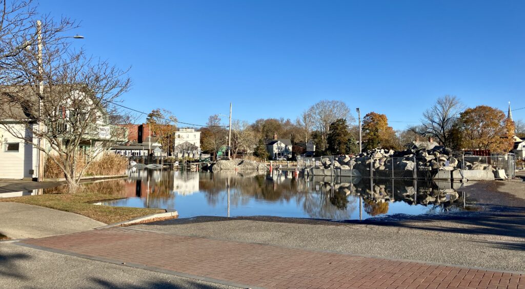 a pond with a brick walkway and trees and buildings in the background (MyCoast AI)