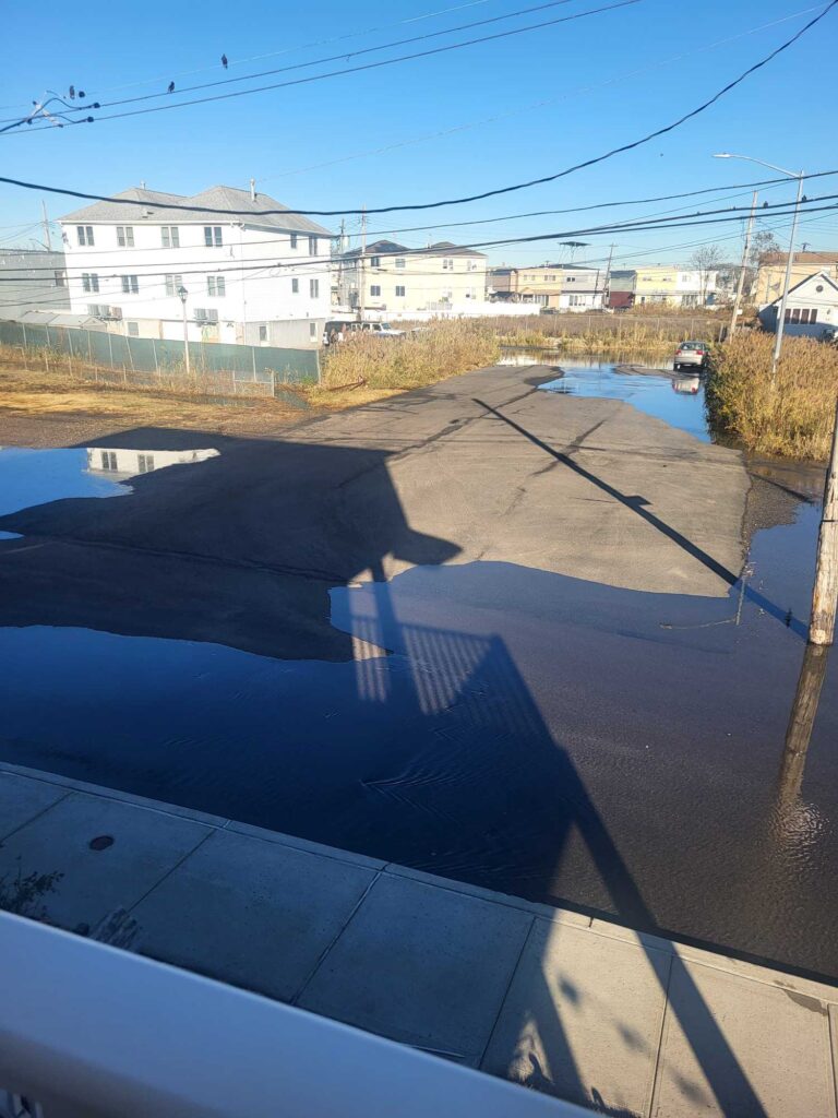 a road with a puddle and buildings on the side (MyCoast AI)