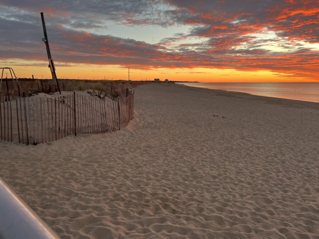 a sandy beach with a fence and a sunset (MyCoast AI)