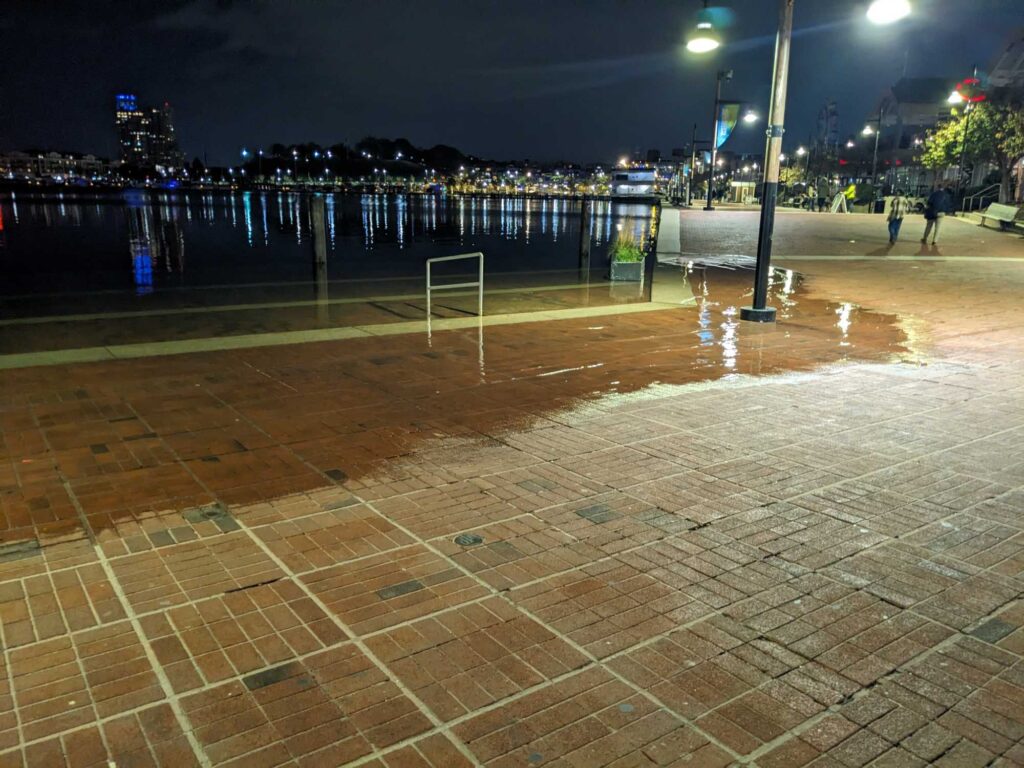 a brick walkway with a body of water and a city in the background (MyCoast AI)