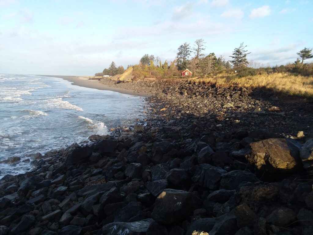 a rocky beach with a house in the distance (MyCoast AI)