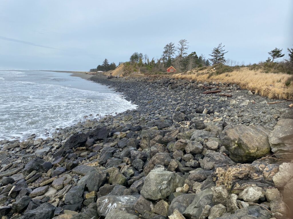 a rocky beach with a house in the distance (MyCoast AI)