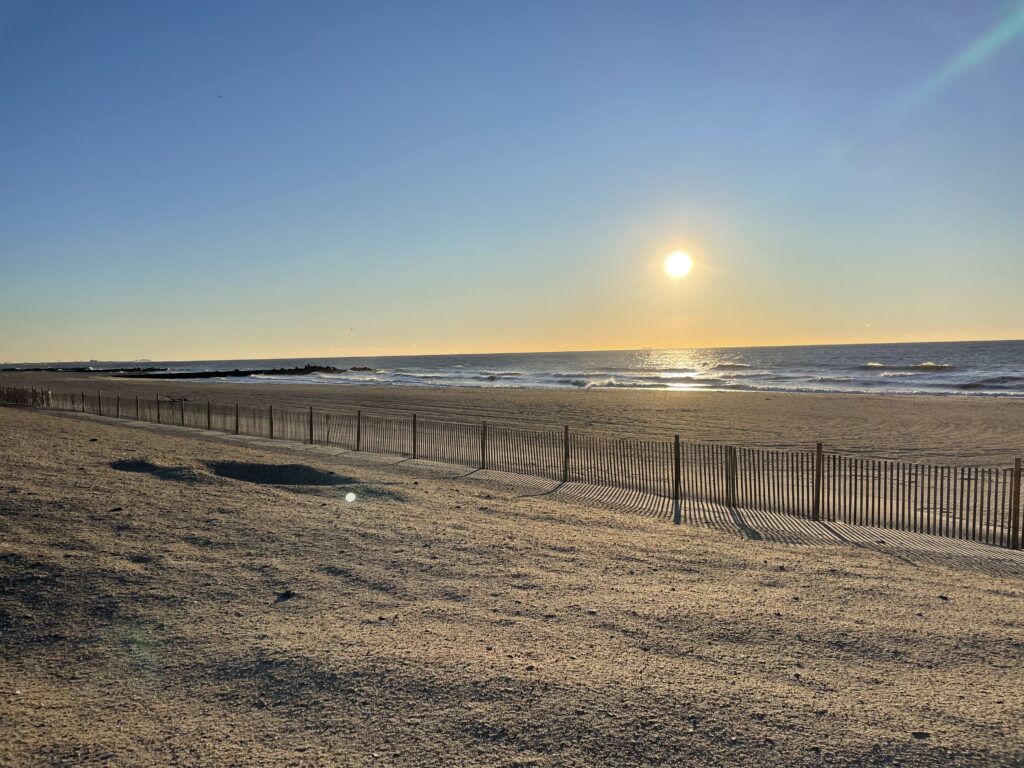 a beach with a fence and the sun in the background (MyCoast AI)