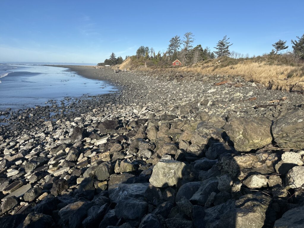 a rocky beach with a house in the background (MyCoast AI)