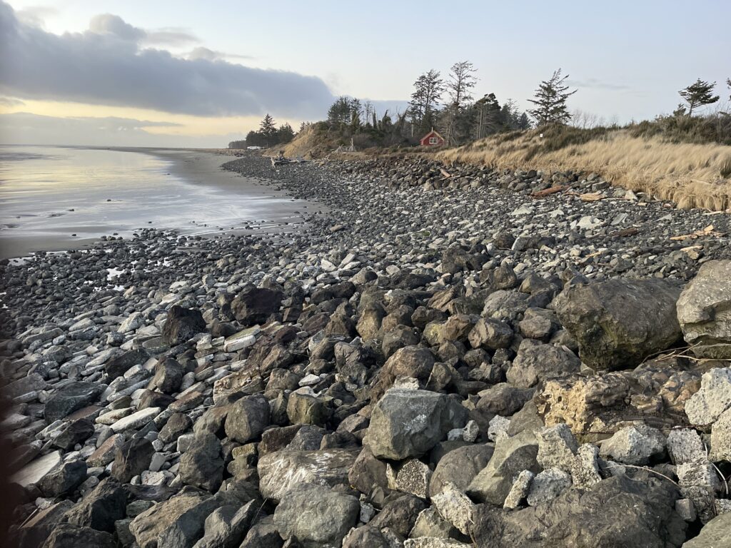 a rocky beach with a house in the distance (MyCoast AI)