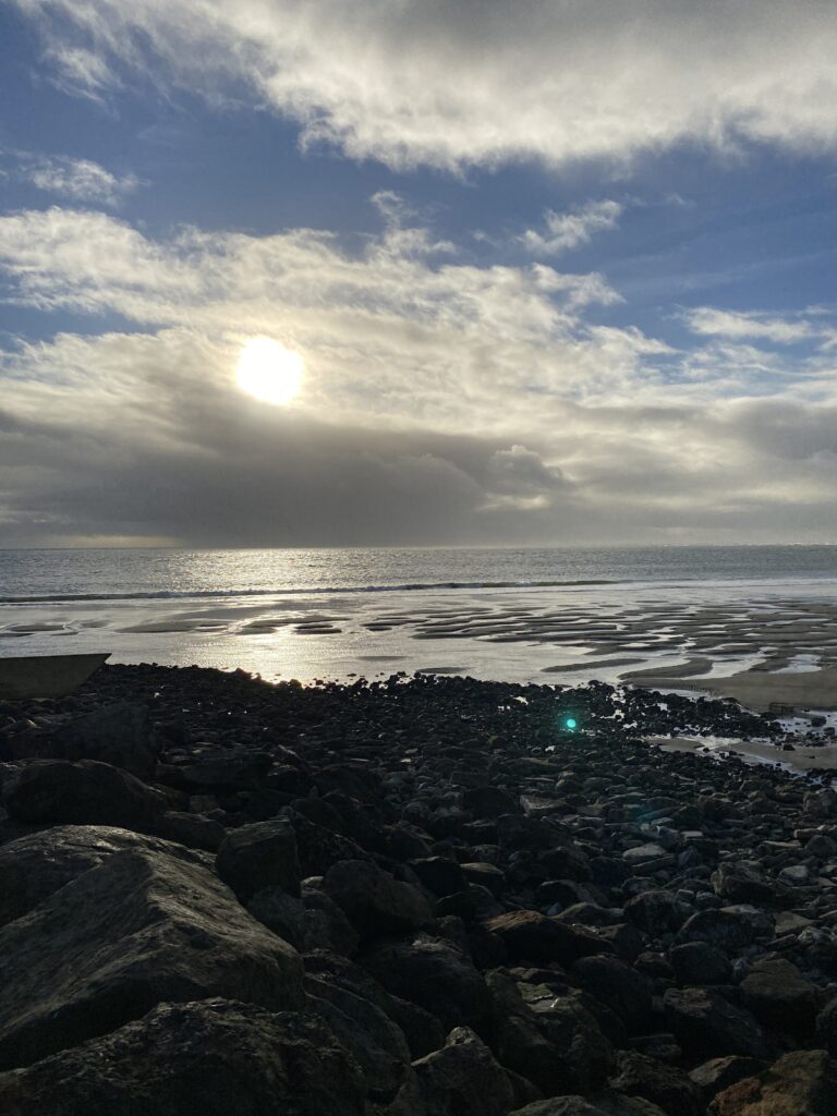 a rocky beach with the sun in the sky (MyCoast AI)