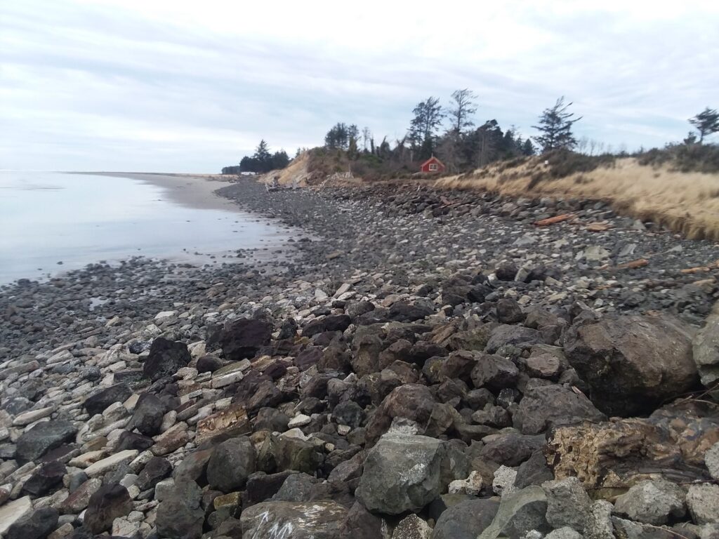 a rocky beach with a house in the distance (MyCoast AI)