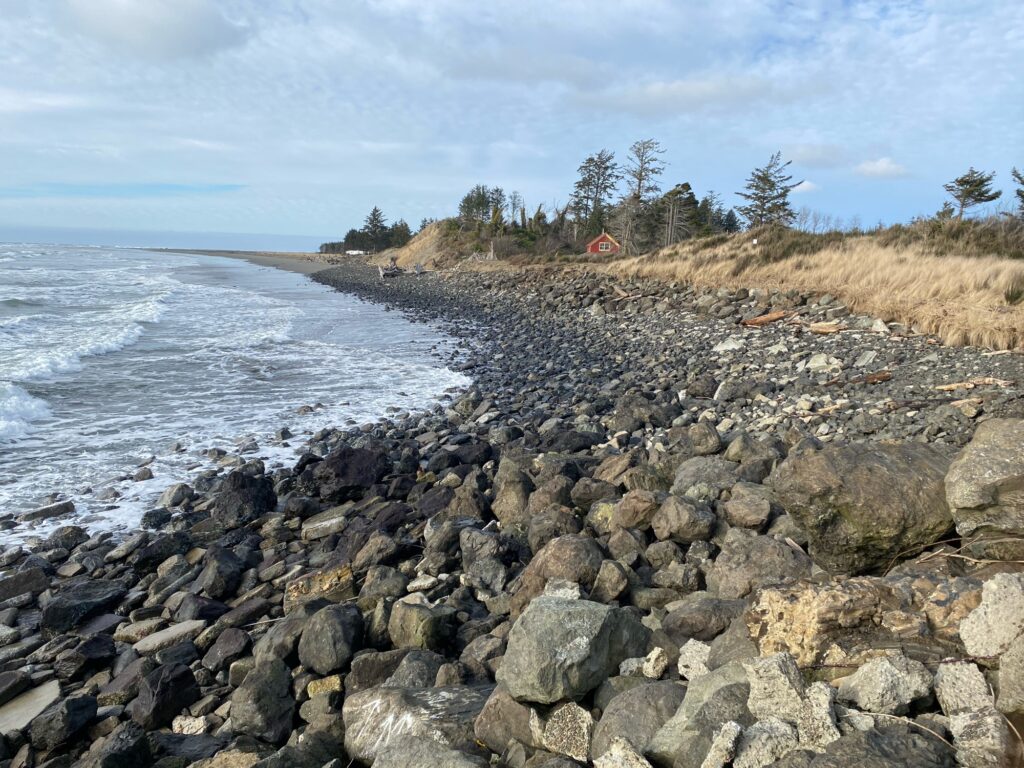 a rocky beach with a house in the distance (MyCoast AI)