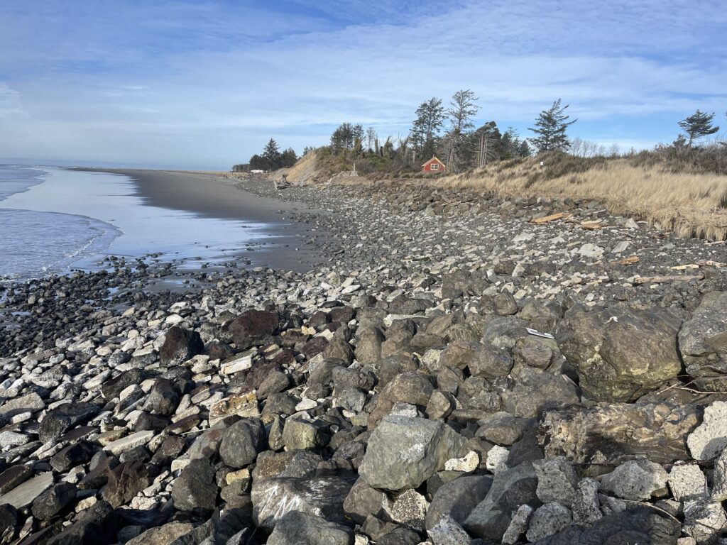 a rocky beach with a house in the background (MyCoast AI)