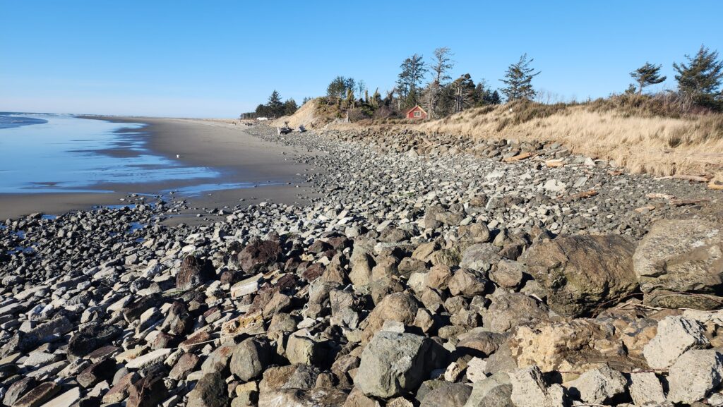 a rocky beach with a house in the distance (MyCoast AI)
