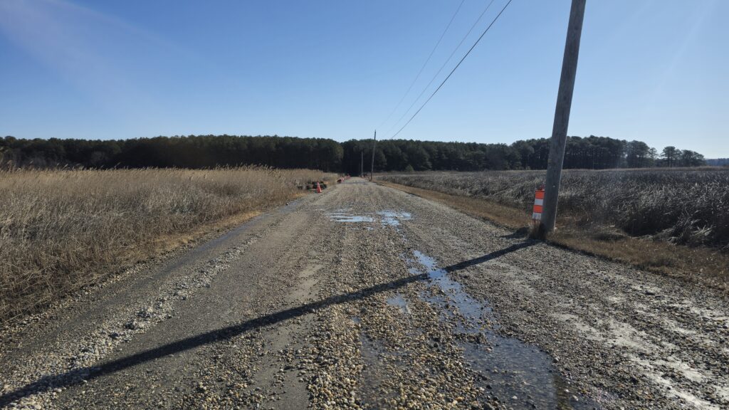 a dirt road with a puddle on the side (MyCoast AI)