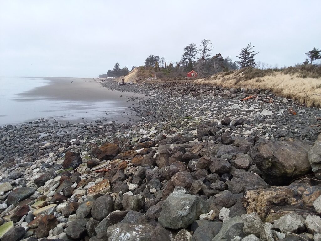 a rocky beach with a house in the distance (MyCoast AI)