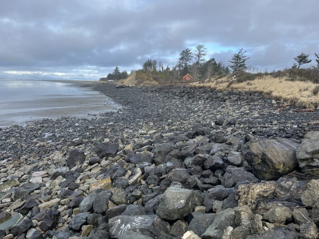 a rocky beach with a house in the distance (MyCoast AI)