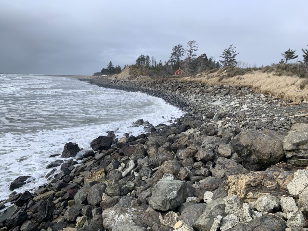 a rocky beach with a house in the distance (MyCoast AI)