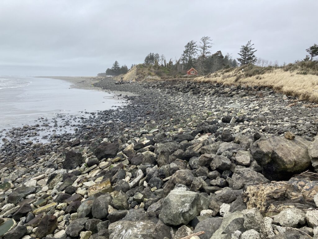 a rocky beach with a house in the distance (MyCoast AI)
