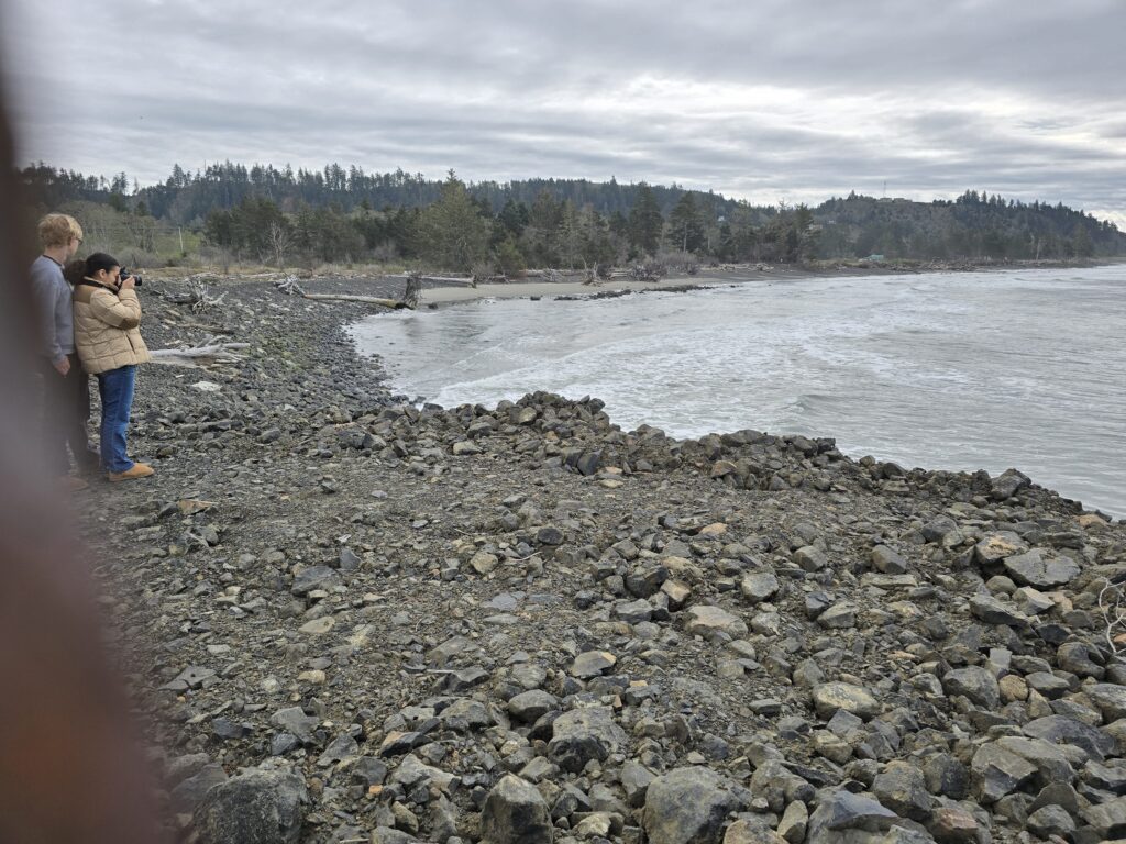 a couple of people standing on a rocky shore by a body of water (MyCoast AI)