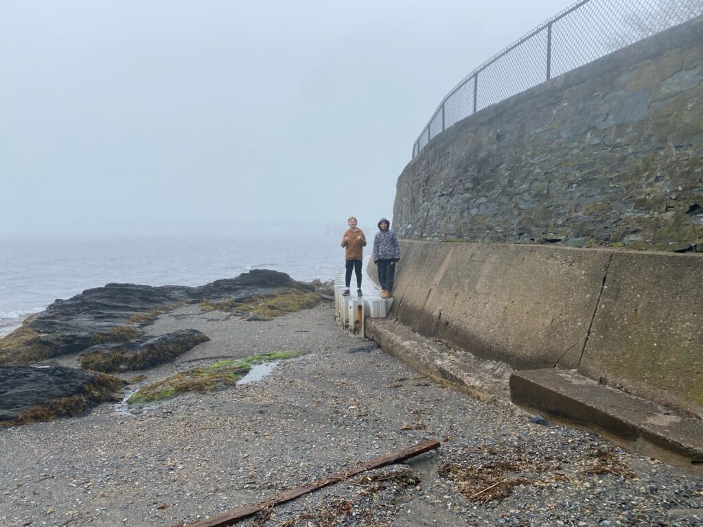 a couple of people walking on a path by a wall and water (MyCoast AI)
