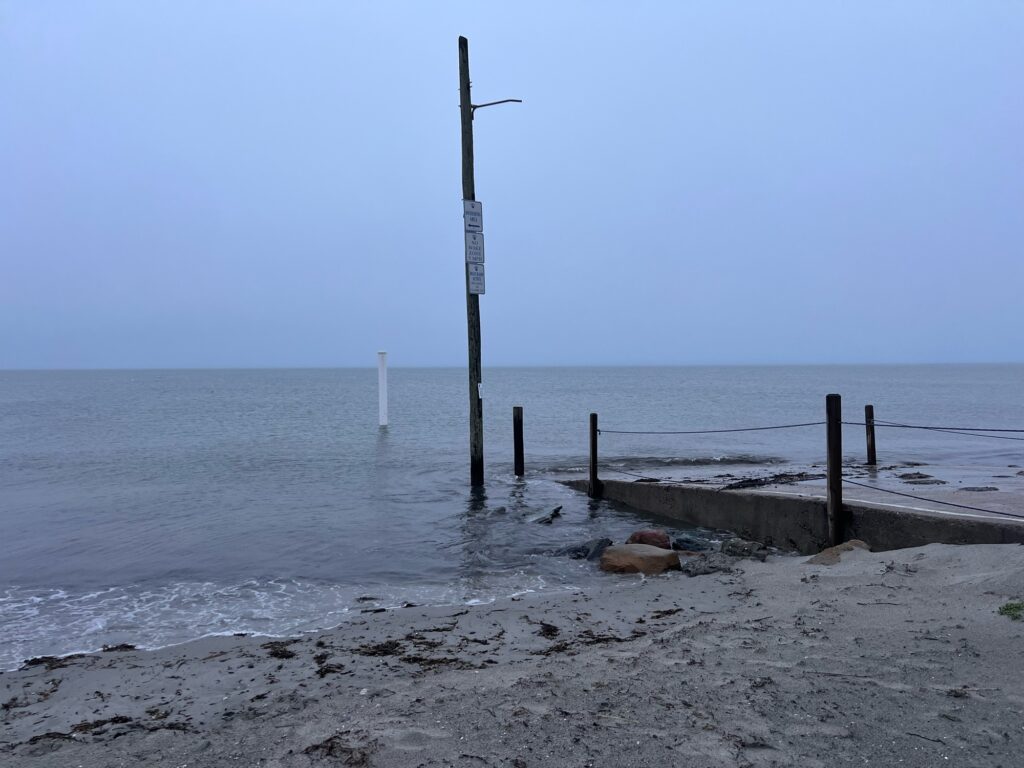 a beach with a pole and a body of water in the background (MyCoast AI)