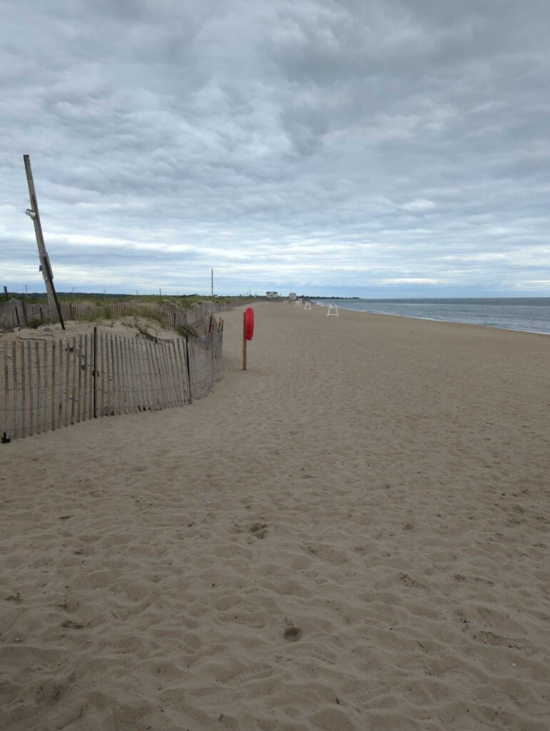 a sandy beach with a fence and a red post (MyCoast AI)