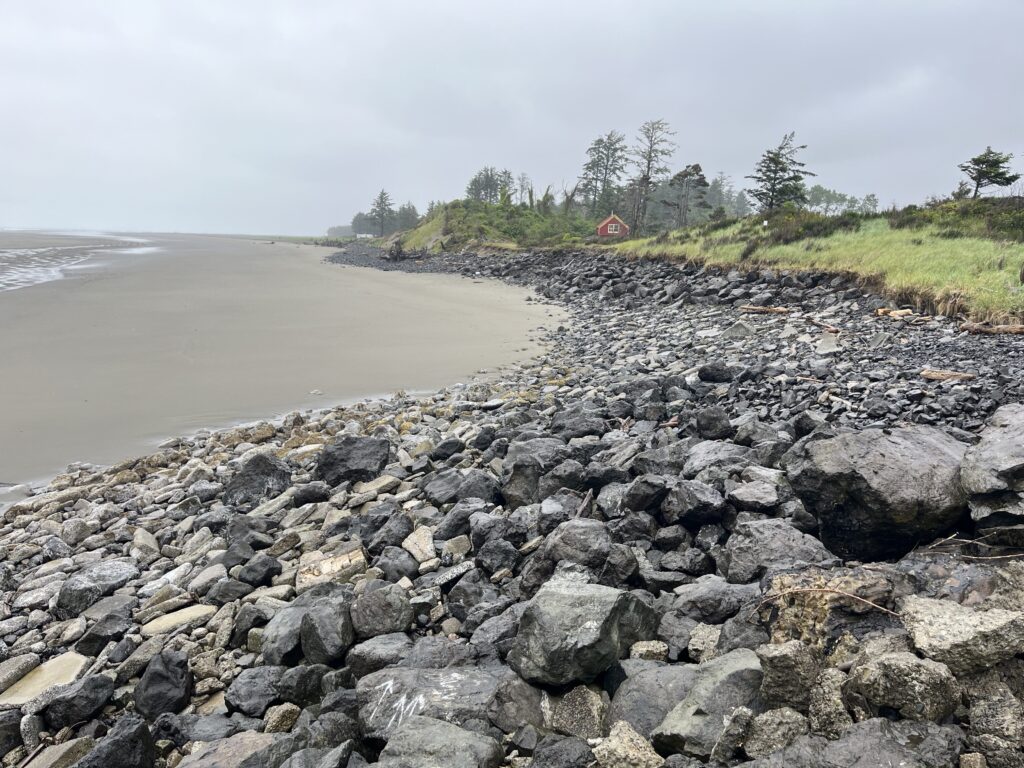 a rocky beach with a house in the distance (MyCoast AI)
