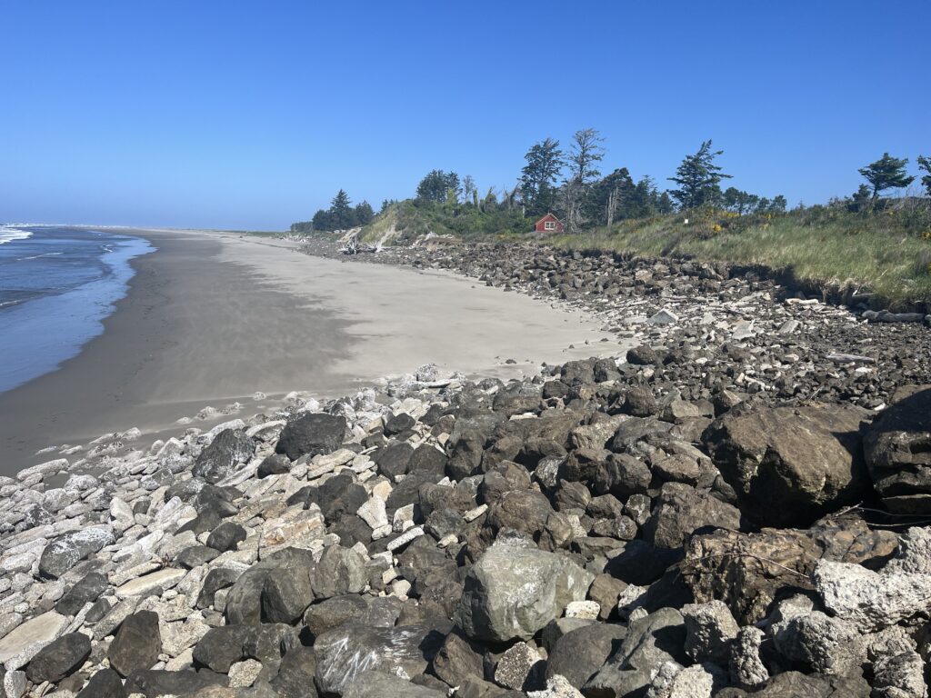 a rocky beach with a house in the distance (MyCoast AI)