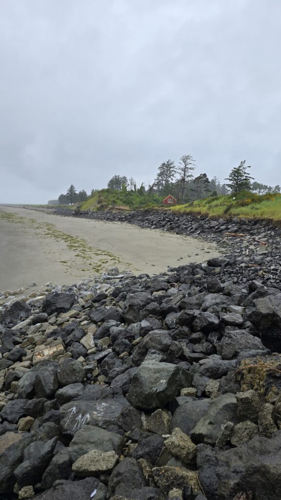 a rocky beach with a house in the background (MyCoast AI)