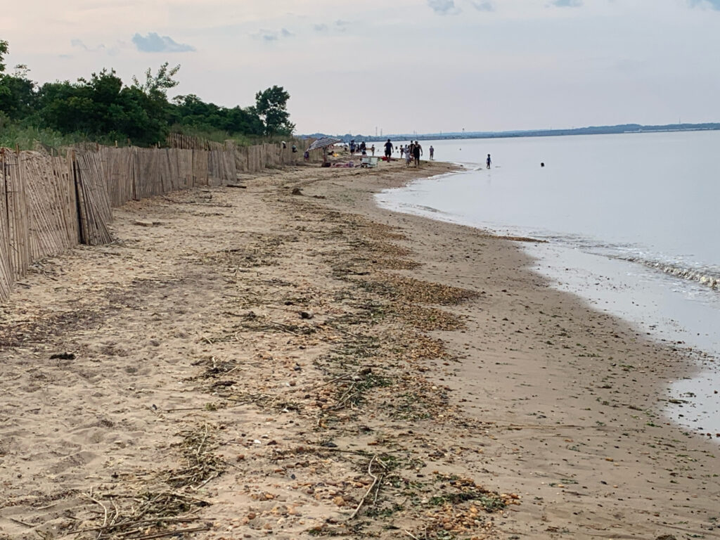 a sandy beach with a fence and people walking on it (MyCoast AI)