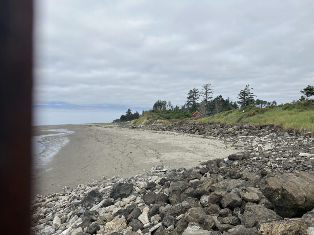 a rocky beach with a house in the distance (MyCoast AI)