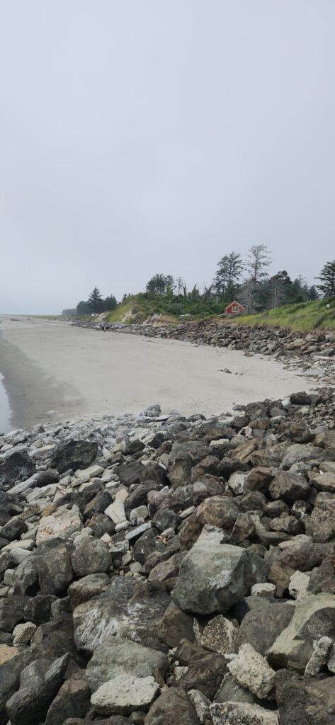 a rocky beach with a house in the background (MyCoast AI)