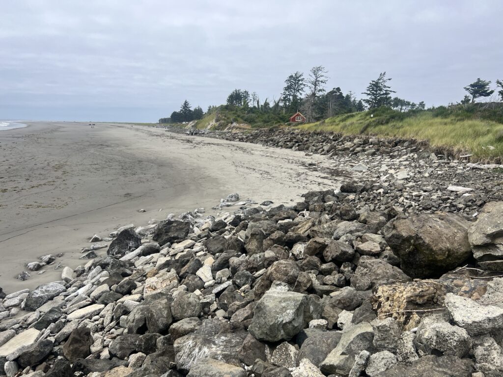 a rocky beach with a house in the distance (MyCoast AI)
