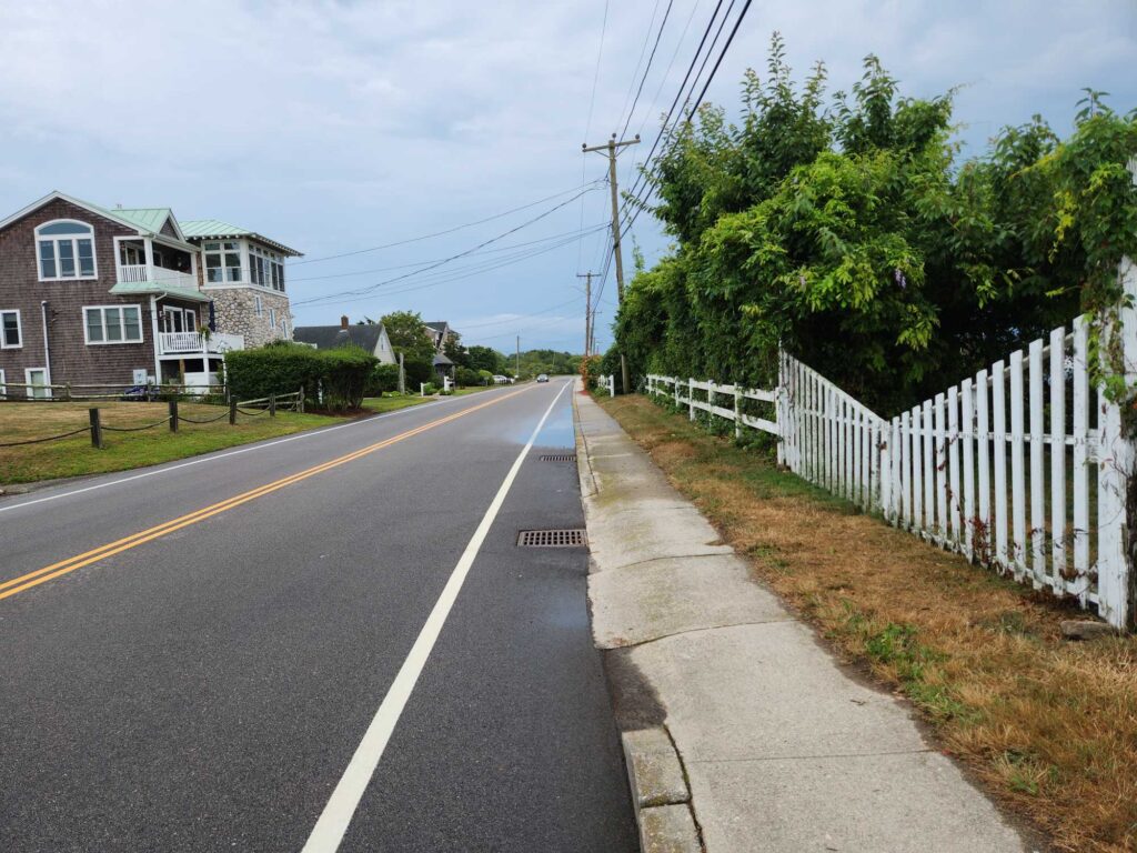 a road with a white fence and trees on the side (MyCoast AI)