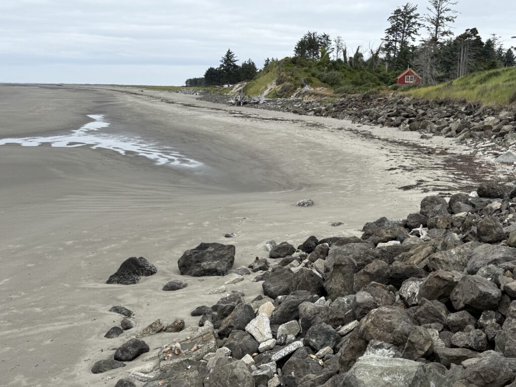 a rocky beach with a house in the background (MyCoast AI)