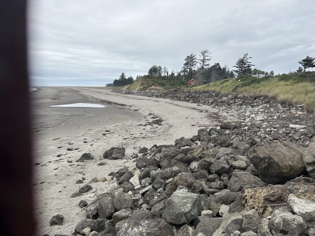 a rocky beach with a house in the distance (MyCoast AI)