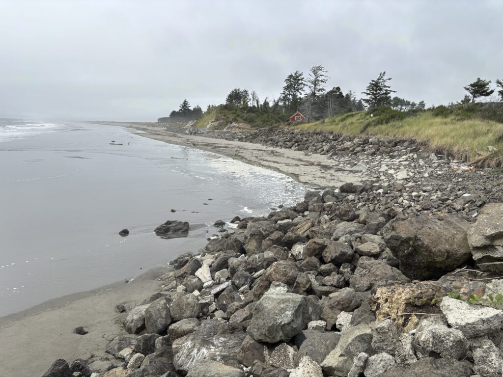 a rocky beach with a house in the distance (MyCoast AI)
