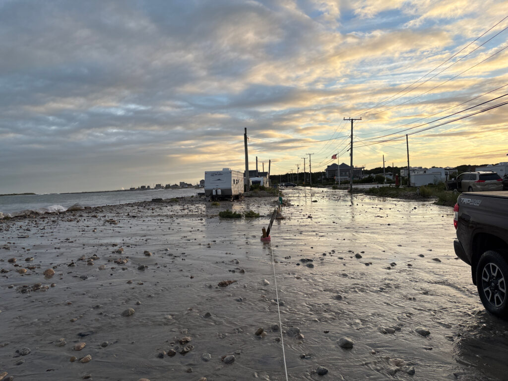 a beach with a car parked on it and a building in the distance (MyCoast AI)