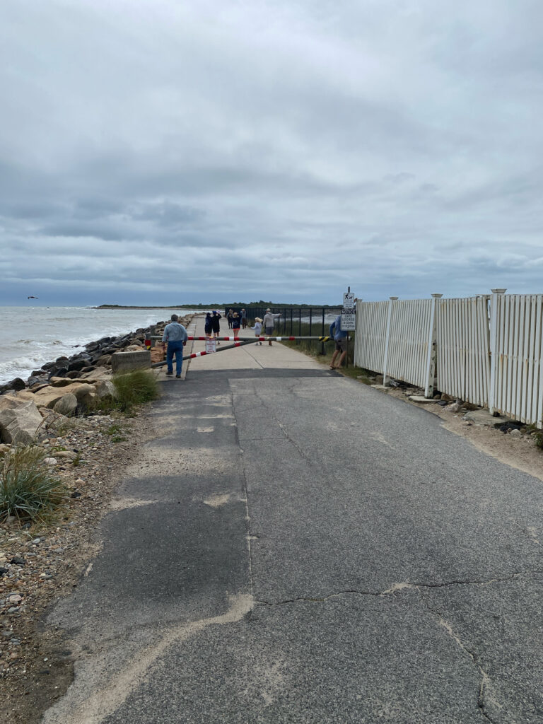 a road with a white fence along it and people walking on the side (MyCoast AI)