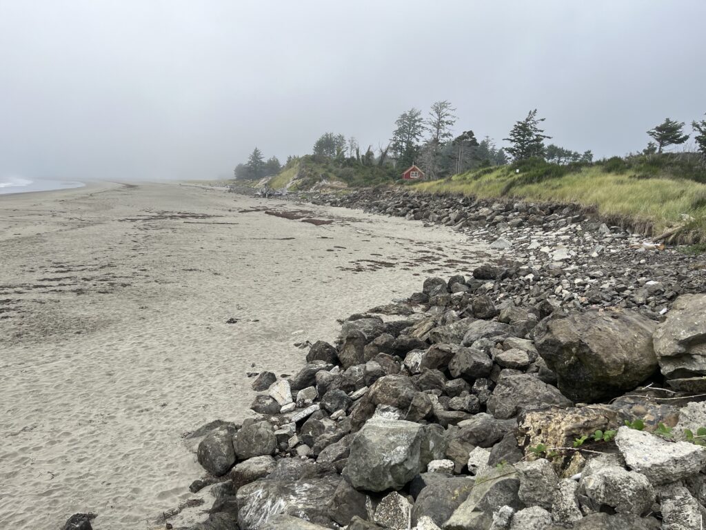 a rocky beach with a house in the distance (MyCoast AI)
