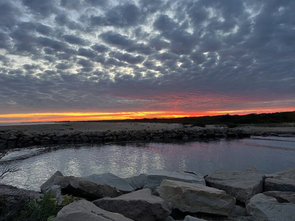 a body of water with rocks and a sunset in the background (MyCoast AI)