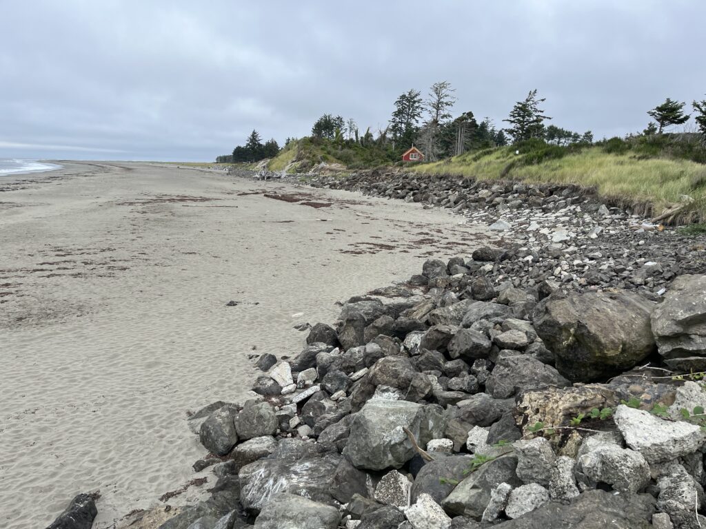 a rocky beach with a house in the background (MyCoast AI)
