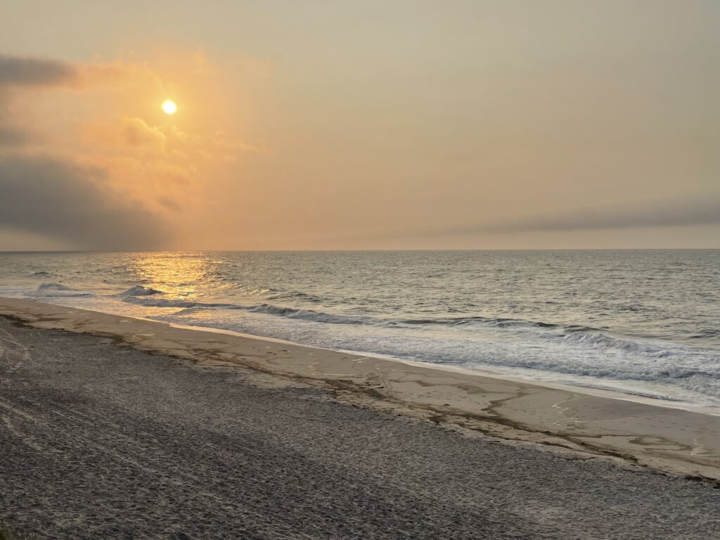 a beach with waves and the sun setting (MyCoast AI)