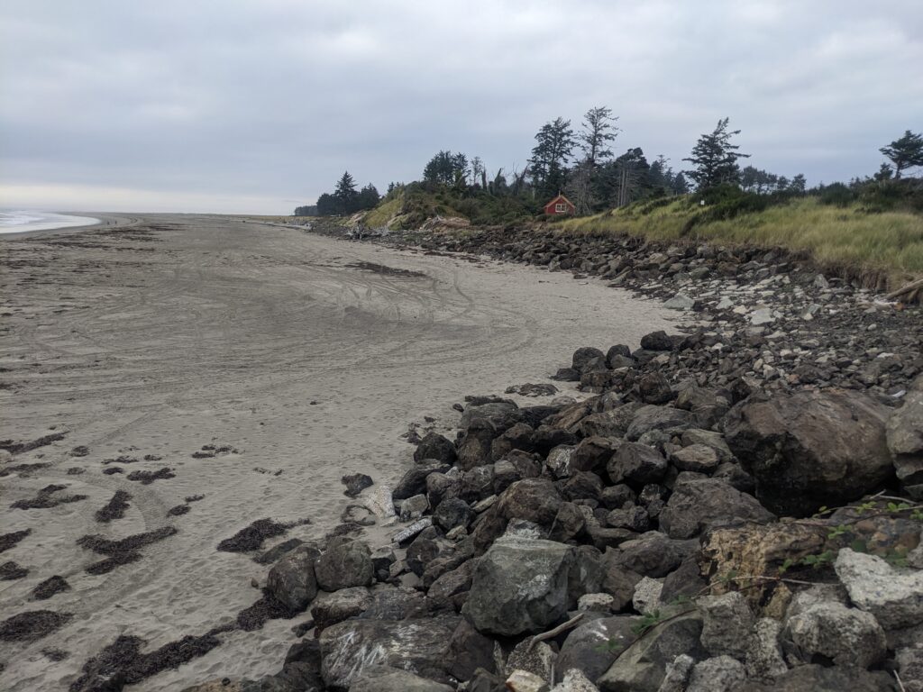 a rocky beach with a house in the distance (MyCoast AI)