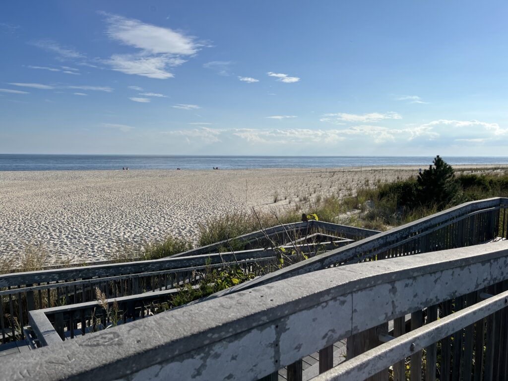 a rail road going through a rocky area with a beach and blue sky (MyCoast AI)
